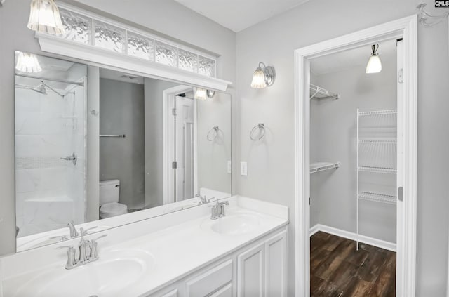 bathroom featuring a sink, wood finished floors, a spacious closet, and toilet