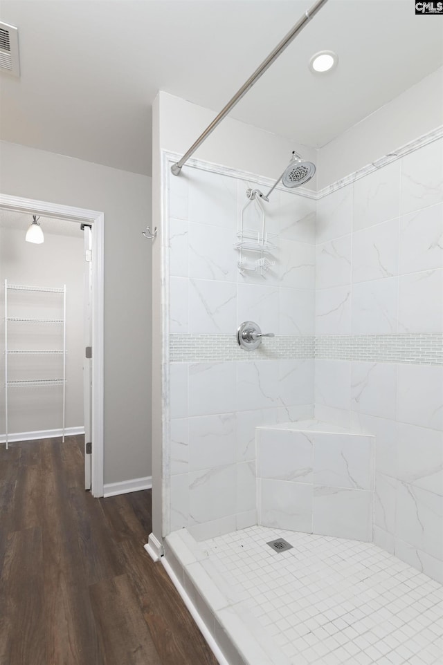 bathroom featuring visible vents, a tile shower, wood finished floors, baseboards, and recessed lighting