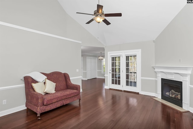 living area featuring high vaulted ceiling, a glass covered fireplace, ceiling fan with notable chandelier, baseboards, and wood finished floors