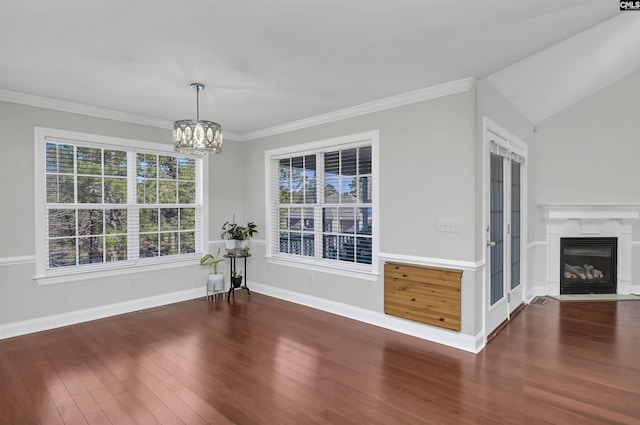 unfurnished dining area with crown molding, a notable chandelier, baseboards, a fireplace with flush hearth, and wood finished floors
