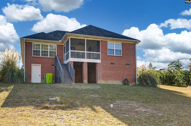 rear view of house featuring a lawn, stairs, a sunroom, and brick siding