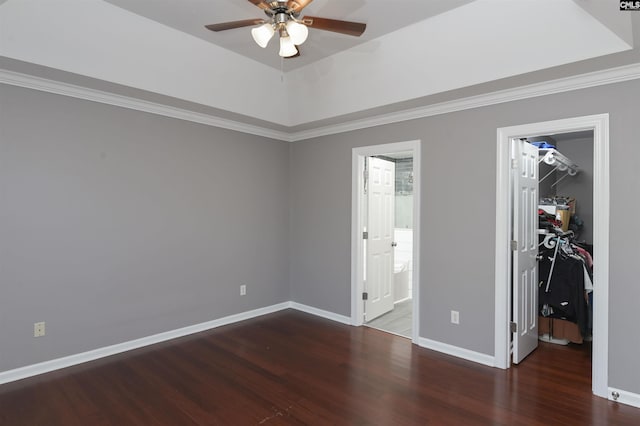 unfurnished bedroom featuring a closet, baseboards, a walk in closet, and wood finished floors