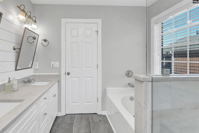 bathroom featuring a bathing tub, double vanity, and a sink