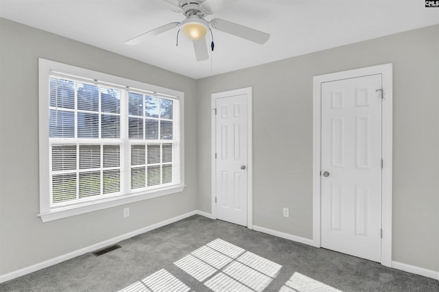 unfurnished bedroom featuring visible vents, multiple windows, and carpet