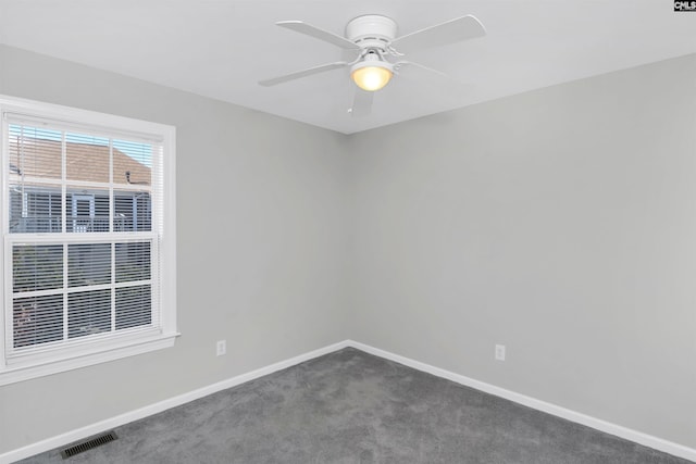 spare room with ceiling fan, visible vents, baseboards, and dark colored carpet