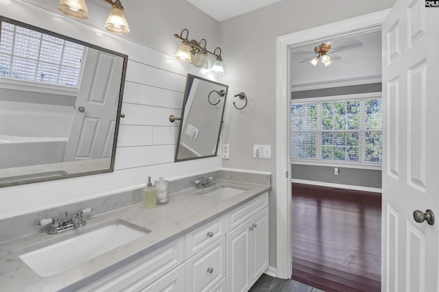 bathroom with a sink, ceiling fan, double vanity, and wood finished floors