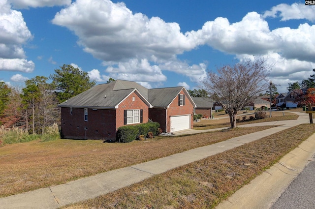 view of front of property with brick siding, an attached garage, driveway, and a front yard
