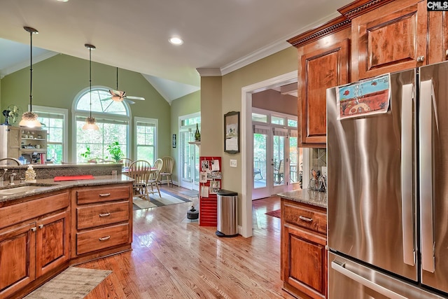 kitchen with crown molding, freestanding refrigerator, a sink, and brown cabinetry
