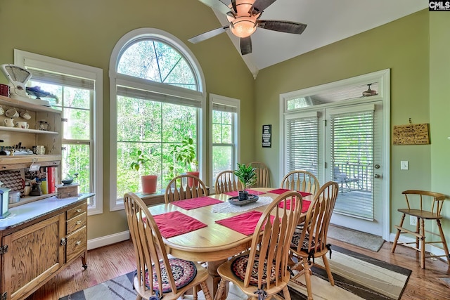dining area featuring baseboards, light wood finished floors, ceiling fan, and vaulted ceiling