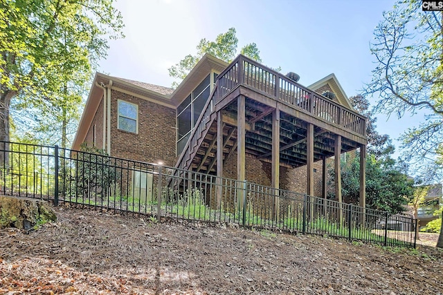 rear view of property with a fenced backyard, a wooden deck, stairway, and brick siding
