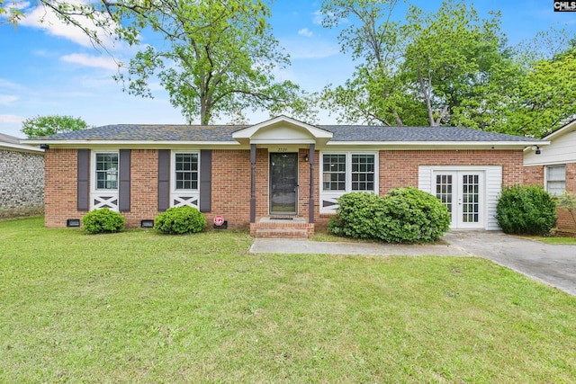 ranch-style house with brick siding, a front lawn, and roof with shingles