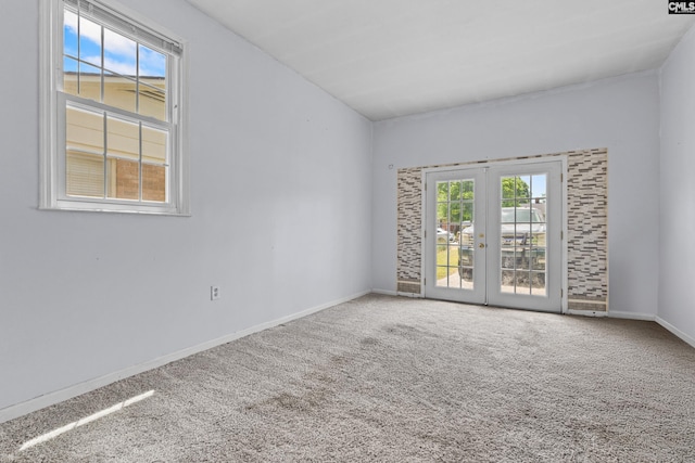carpeted empty room featuring french doors and baseboards