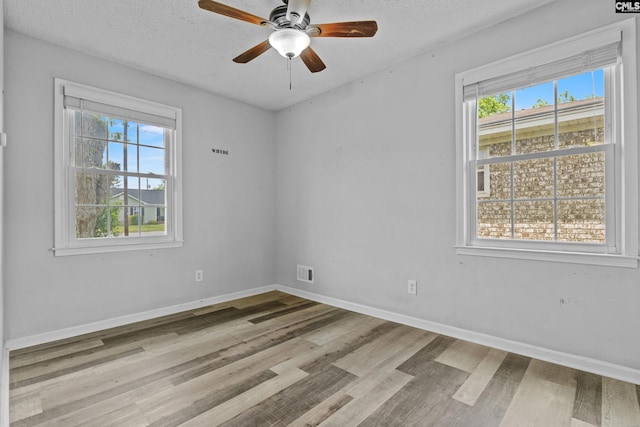 spare room with baseboards, ceiling fan, visible vents, and wood finished floors