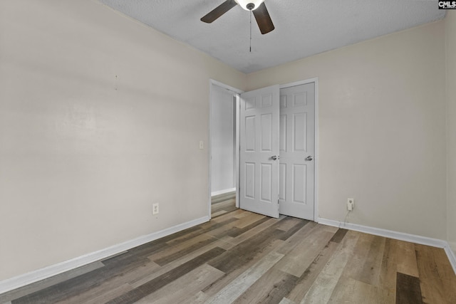 unfurnished bedroom with a ceiling fan, baseboards, wood finished floors, and a textured ceiling