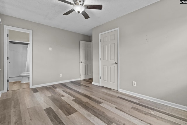 unfurnished bedroom with a textured ceiling, baseboards, and wood finished floors
