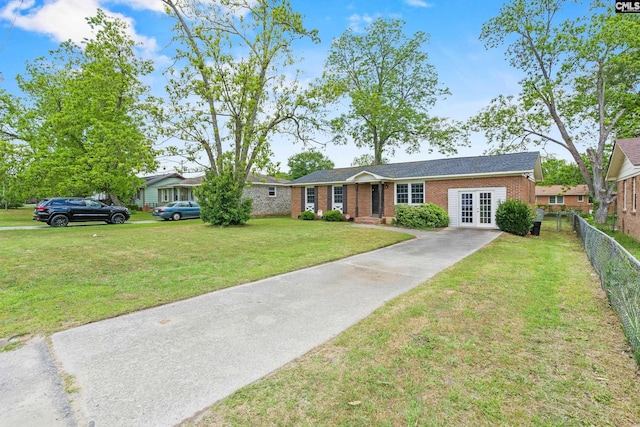 single story home featuring fence, a front yard, french doors, brick siding, and driveway