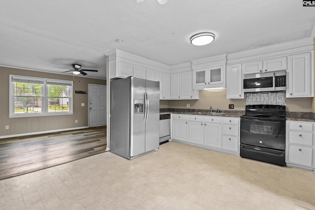 kitchen with dark countertops, appliances with stainless steel finishes, white cabinets, and a ceiling fan