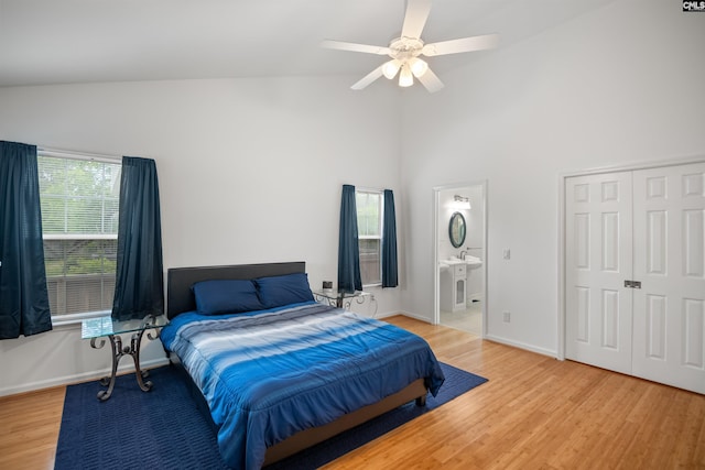 bedroom with connected bathroom, ceiling fan, high vaulted ceiling, baseboards, and light wood-type flooring