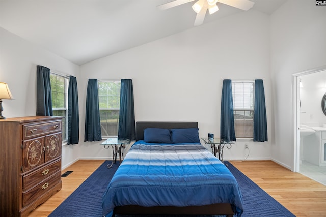 bedroom featuring light wood-style floors, high vaulted ceiling, ensuite bathroom, and baseboards