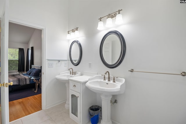 bathroom with ensuite bathroom, two sinks, and marble finish floor