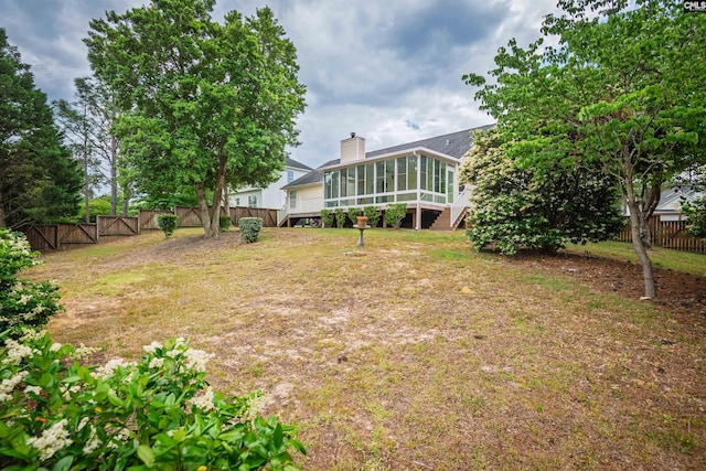 view of yard with fence, a gate, and a sunroom