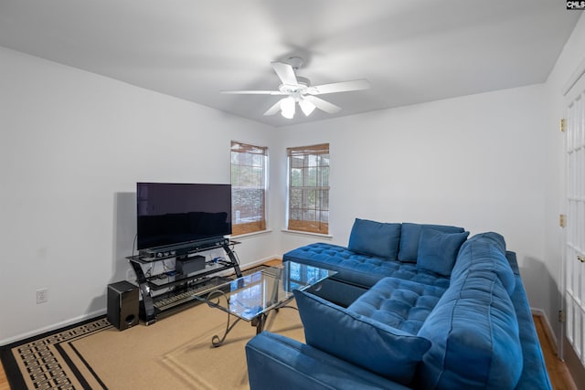 living area with baseboards, ceiling fan, and wood finished floors