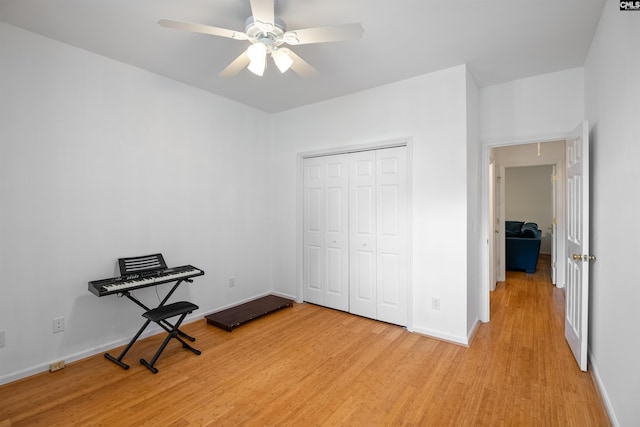 unfurnished bedroom with a closet, baseboards, attic access, light wood-type flooring, and a ceiling fan