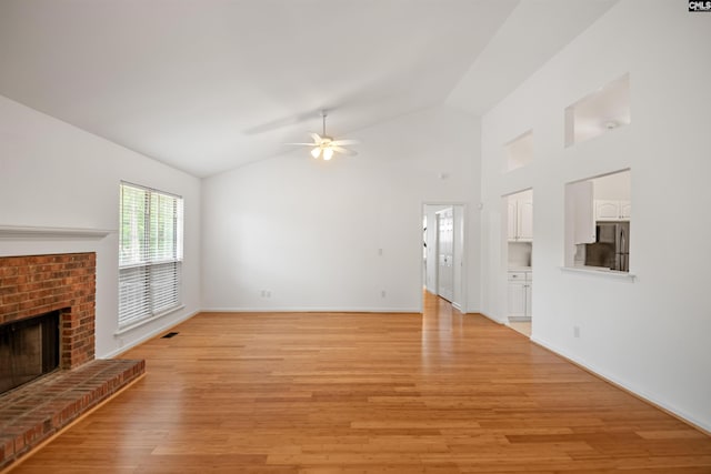 unfurnished living room featuring a brick fireplace, a ceiling fan, baseboards, light wood-type flooring, and vaulted ceiling