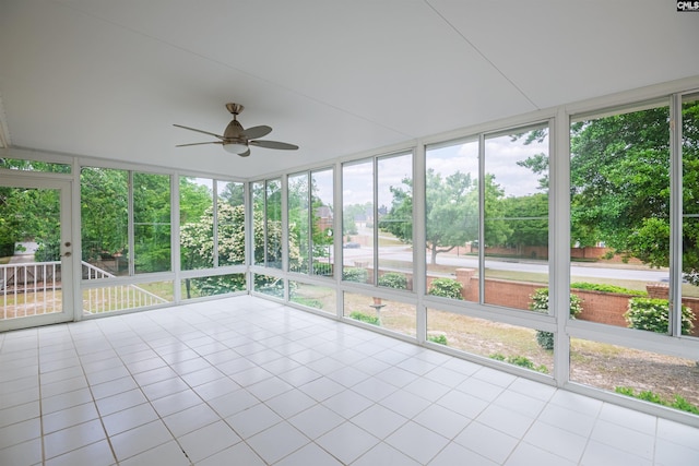 unfurnished sunroom featuring a ceiling fan, a healthy amount of sunlight, and tile patterned flooring