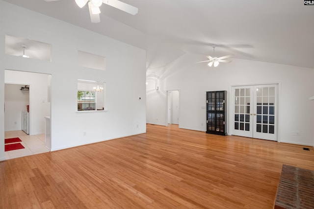 unfurnished living room with light wood-style flooring, lofted ceiling, french doors, and ceiling fan with notable chandelier