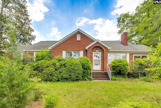 bungalow-style house featuring brick siding, a front lawn, and a chimney
