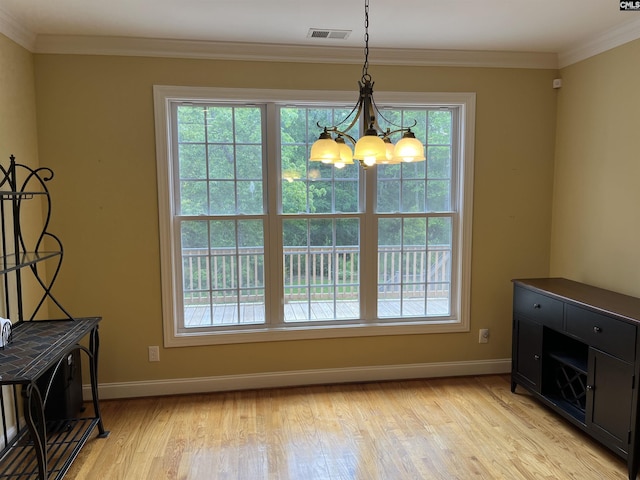 dining area featuring visible vents, crown molding, light wood-type flooring, baseboards, and a notable chandelier