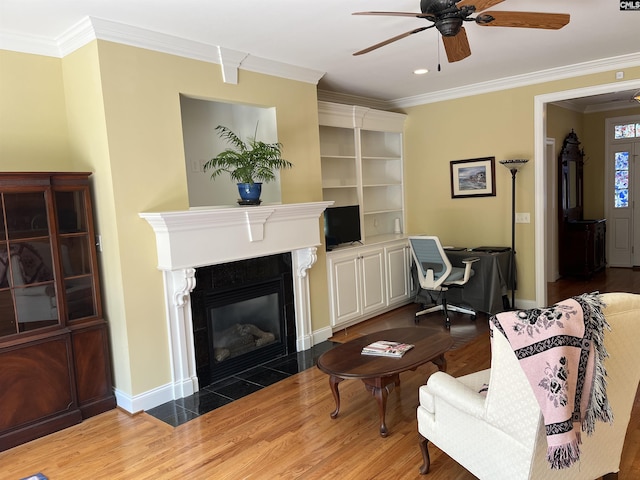 living room with ornamental molding, a ceiling fan, and wood finished floors