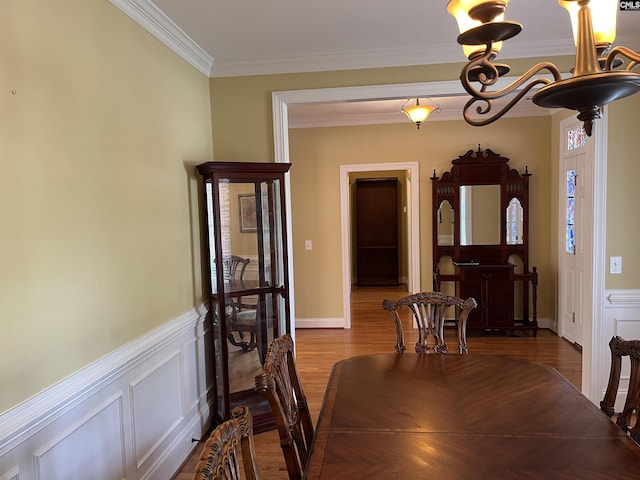 dining room with crown molding, a wainscoted wall, and wood finished floors