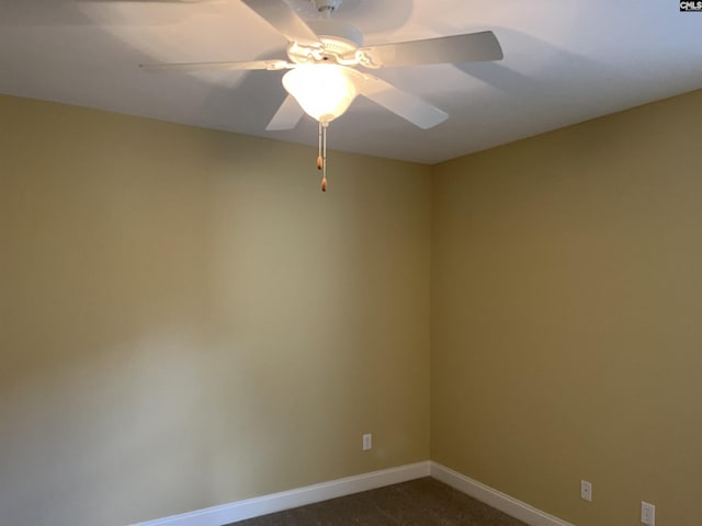spare room featuring a ceiling fan, baseboards, and dark colored carpet