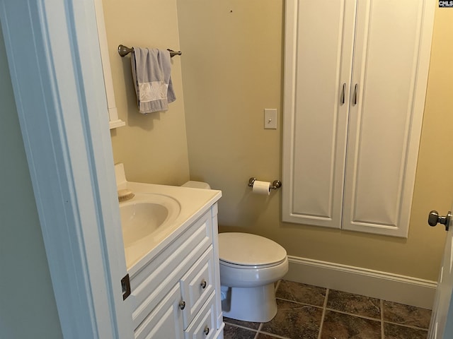 half bath with toilet, baseboards, and vanity