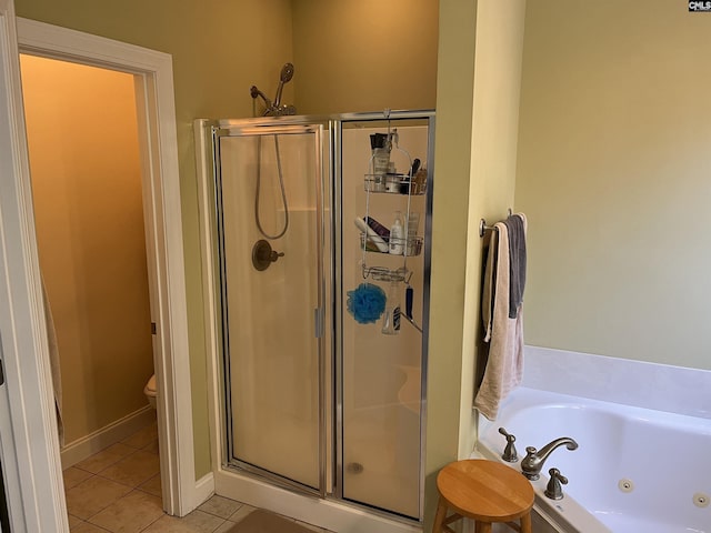 bathroom featuring tile patterned flooring, toilet, baseboards, a tub with jets, and a shower stall