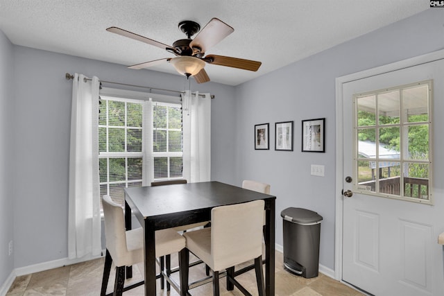 dining space with baseboards, a ceiling fan, and a textured ceiling