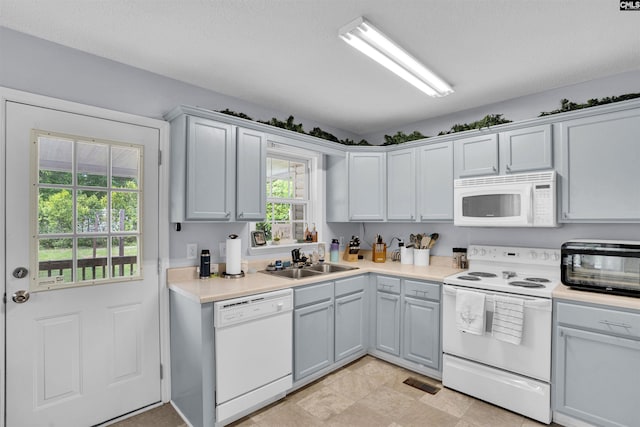 kitchen featuring a toaster, white appliances, light countertops, gray cabinets, and a sink