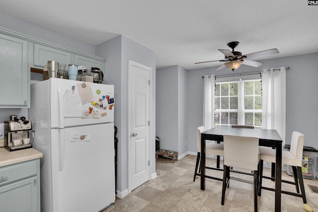 kitchen featuring freestanding refrigerator, a textured ceiling, ceiling fan, and light countertops