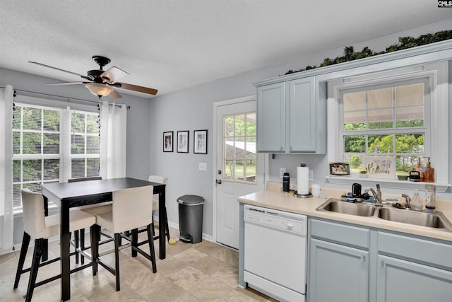 kitchen with baseboards, ceiling fan, a textured ceiling, a sink, and dishwasher