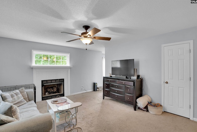 carpeted living room featuring a tiled fireplace, a textured ceiling, and ceiling fan