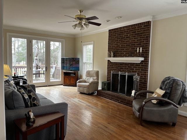 living room with a ceiling fan, ornamental molding, wood finished floors, and a fireplace
