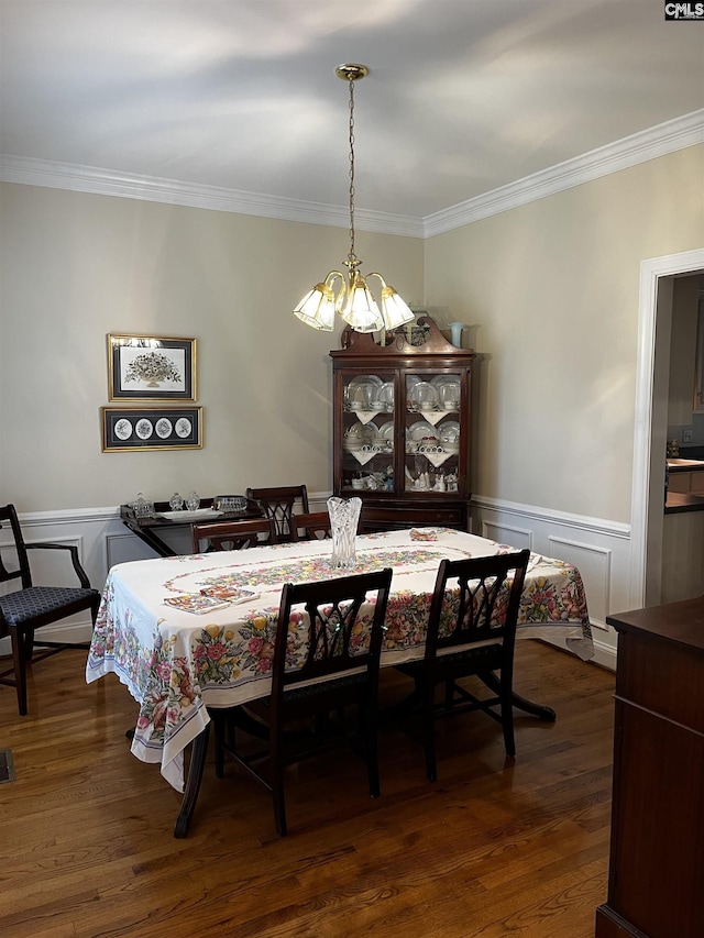 dining room featuring crown molding, a chandelier, wainscoting, and dark wood finished floors