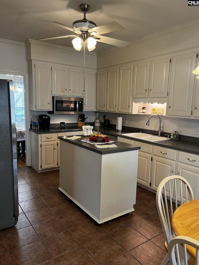kitchen with dark countertops, appliances with stainless steel finishes, crown molding, and white cabinetry