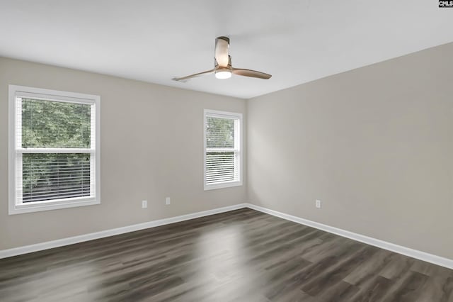 unfurnished room featuring baseboards, ceiling fan, and dark wood-type flooring
