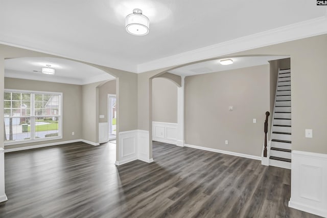 unfurnished living room with crown molding, dark wood-style flooring, arched walkways, and stairway