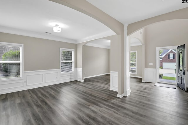 entryway with arched walkways, dark wood finished floors, wainscoting, and ornamental molding