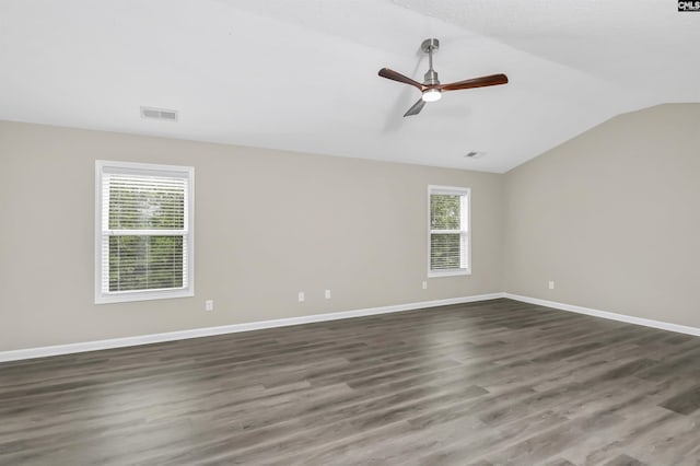 spare room featuring visible vents, baseboards, dark wood-style floors, a ceiling fan, and vaulted ceiling