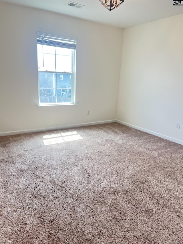 unfurnished room featuring baseboards, visible vents, and carpet